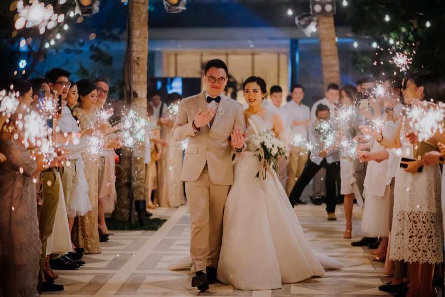 Wedding reception guests holding sparklers with the couple in the middle