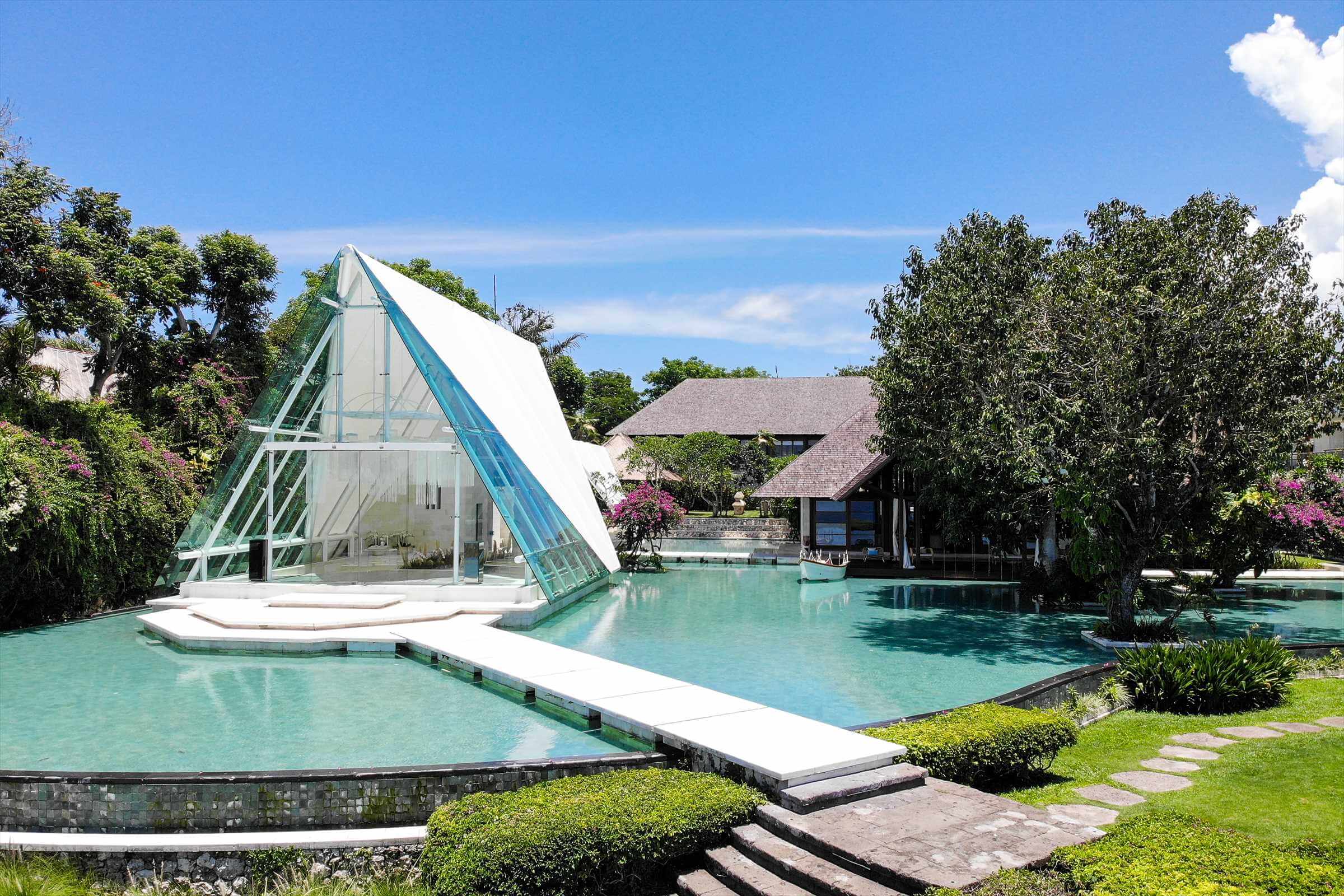 Tirtha Uluwatu's iconic glass wedding chapel stand beautifully surrounded by water, for your stunning wedding in Bali
