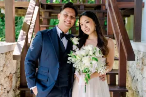 Evelyn and Darrell pose together on a wooden staircase, capturing a joyful moment before their Bali destination wedding at Tirtha.