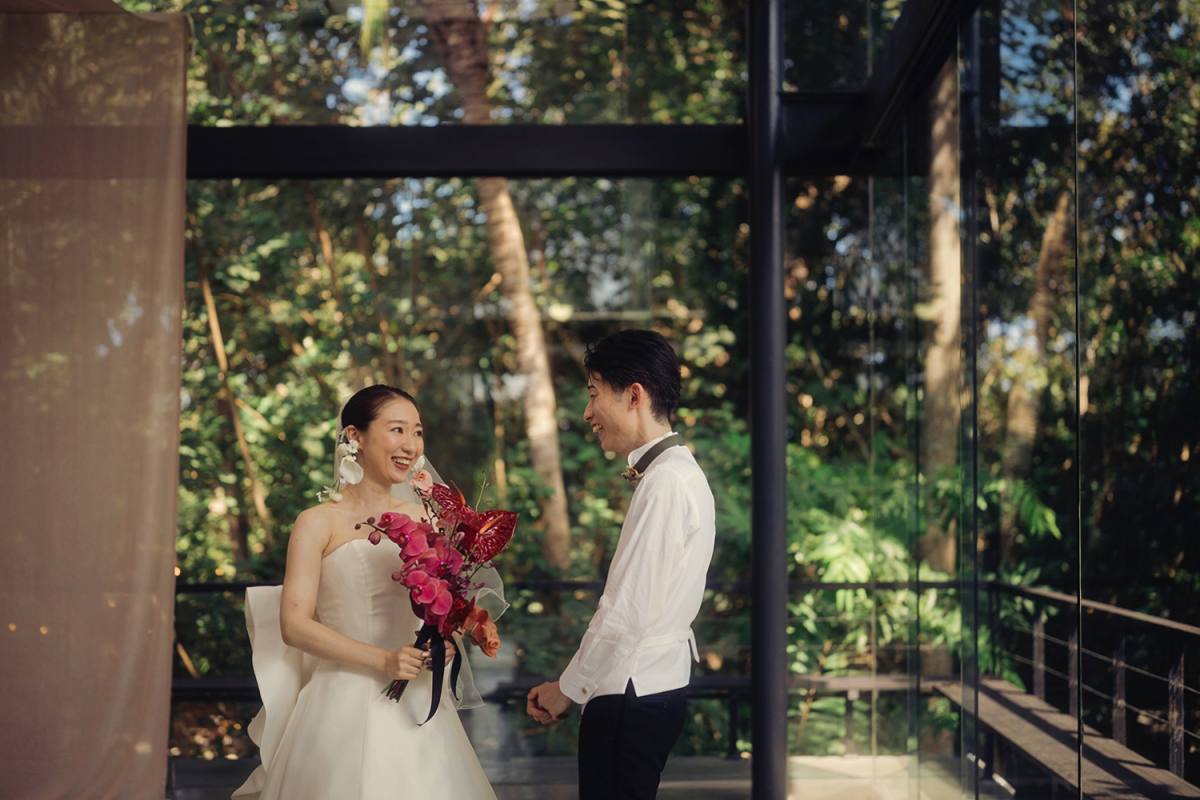A joyful first look between bride and groom inside Plumeria Room, the heart of Tirtha Bali’s greenhouse wedding venue