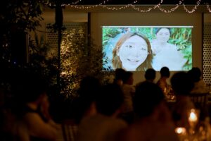 Guests watching the couple’s love story unfold on screen at Tirtha Bali’s Plumeria Room.