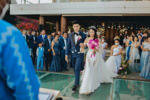 Bride and groom walking down the glass stage aisle at Tirtha Uluwatu wedding.