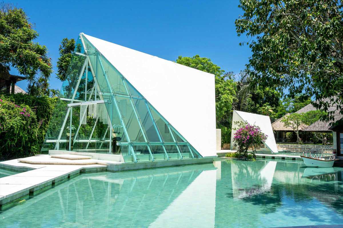 Modern glass wedding chapel in Bali at Tirtha Uluwatu surrounded by water.