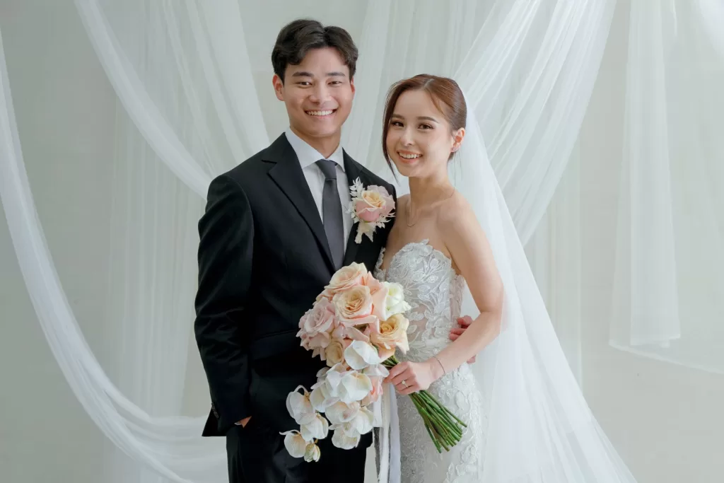 Wan Ting and Keefe smiling with blush rose bouquet at their Bali destination wedding.