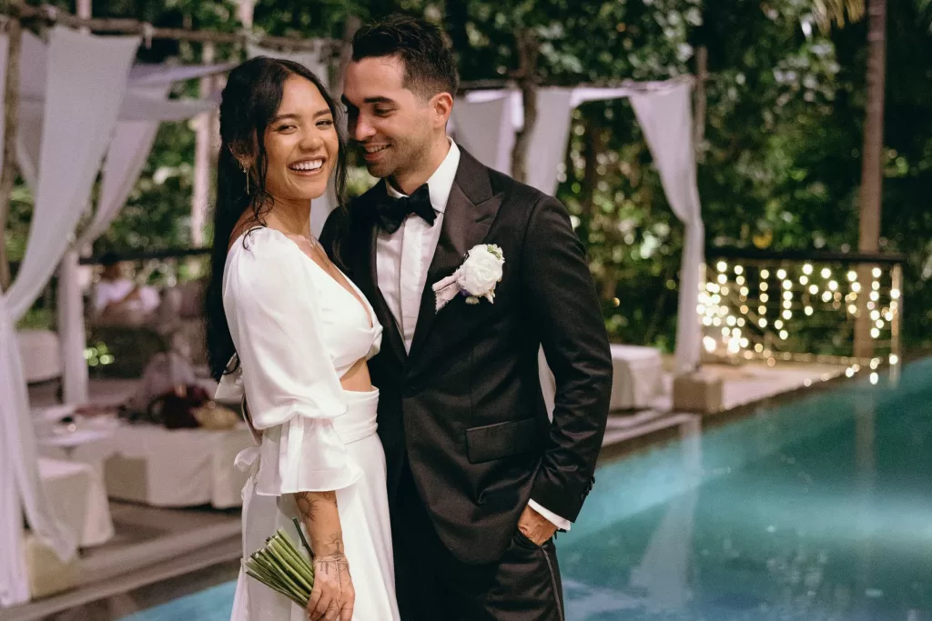 Patty and Davarone smiling by the pool during their Bali destination wedding.
