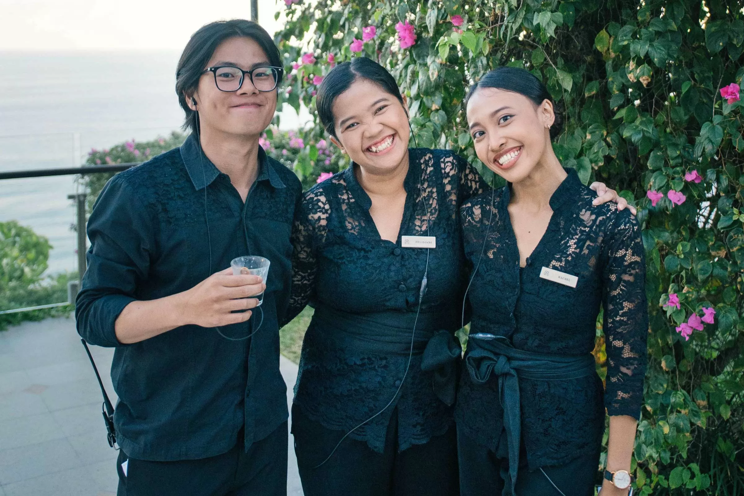 Tirtha Bali wedding planning team smiling together with lush greenery and ocean views in the background.
