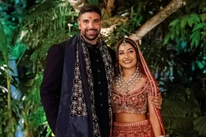 Ishita and Ben in traditional Indian wedding attire at the Glass House by Tirtha with lush greenery behind them.
