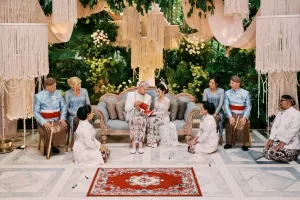 A newlywed couple in traditional attire practices Javanese wedding ritual witnessed by their parents at the Moonlight Garden.