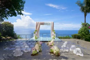 Tirtha Uluwatu’s Glass Stage with pastel decor and ocean views for a clifftop wedding, included in the Scarlett package.