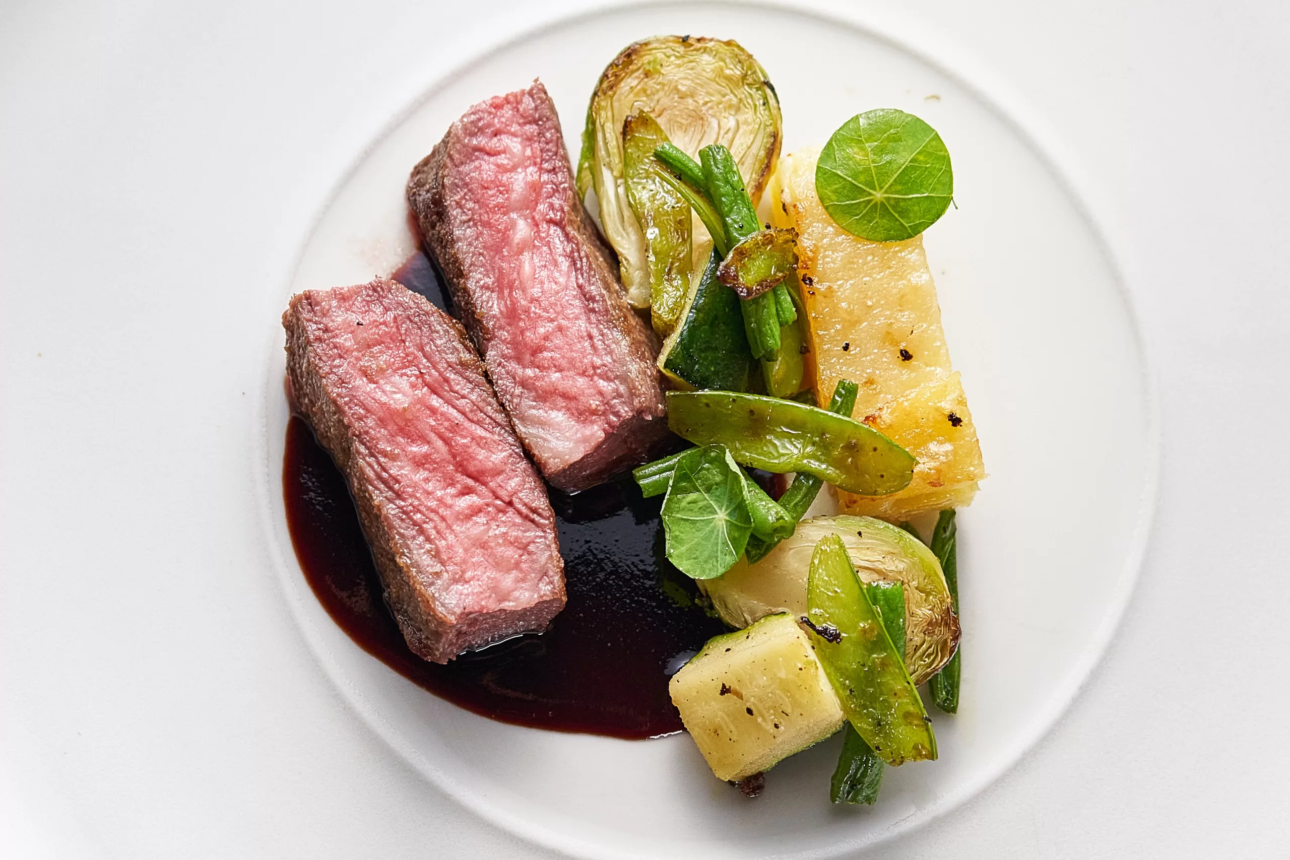 Australian Wagyu beef steak served with red wine sauce and seasonal vegetables on a gourmet plate.