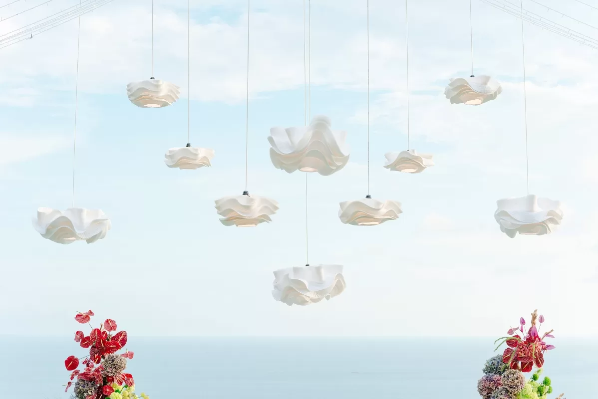Floral lamp installation at Tirtha Uluwatu set against the sky and Indian Ocean view.