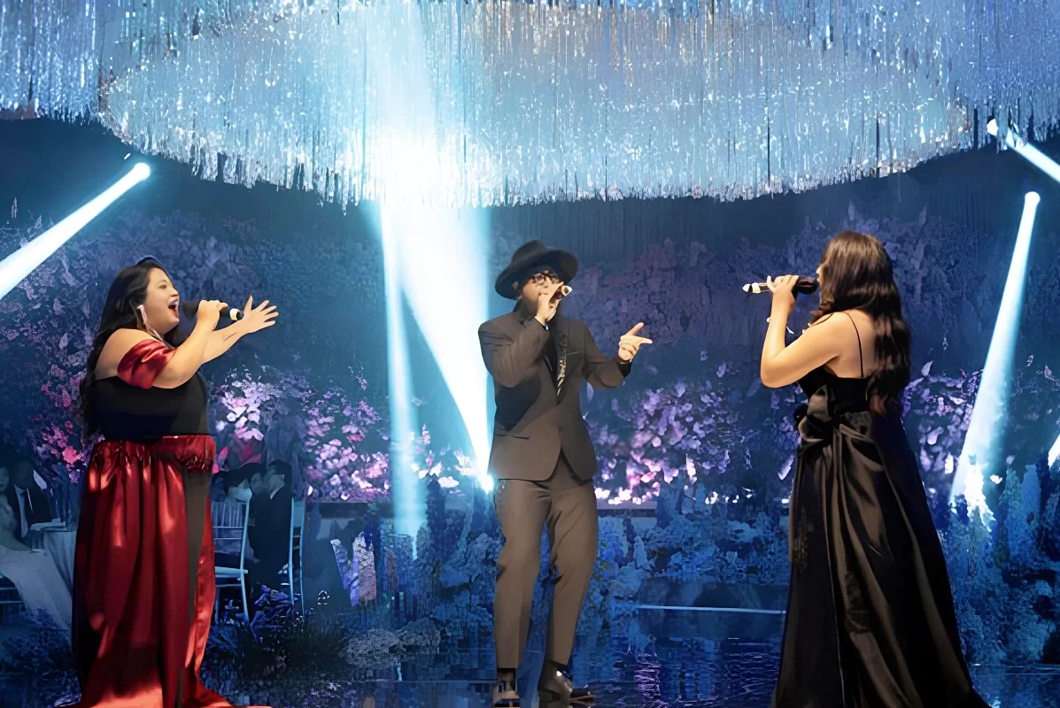Three singers from Luxe Voir perform beneath celling string curtain and dramatic lighting