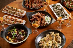 Bali wedding buffet menu featuring assorted dishes, seafood, meats, and canapés, elegantly styled on a wooden dining table.
