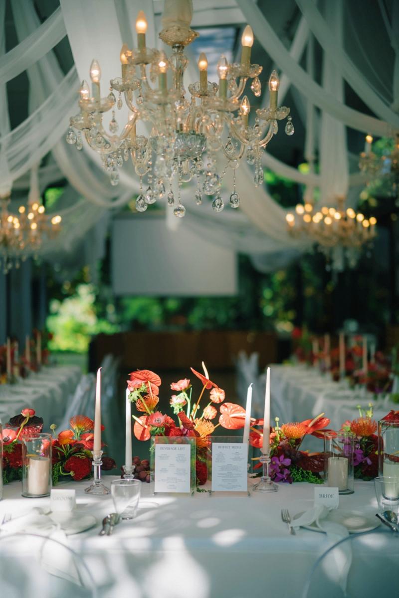 A real wedding reception at the Plumeria Room, styled with chandeliers and vibrant florals.