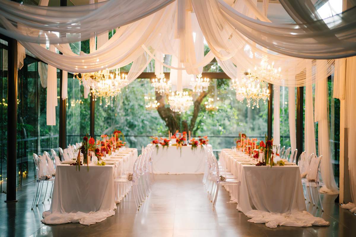 Reception setup at the Plumeria Room, styled with draped fabric, chandeliers, and vibrant florals for a destination wedding at Tirtha Bali.