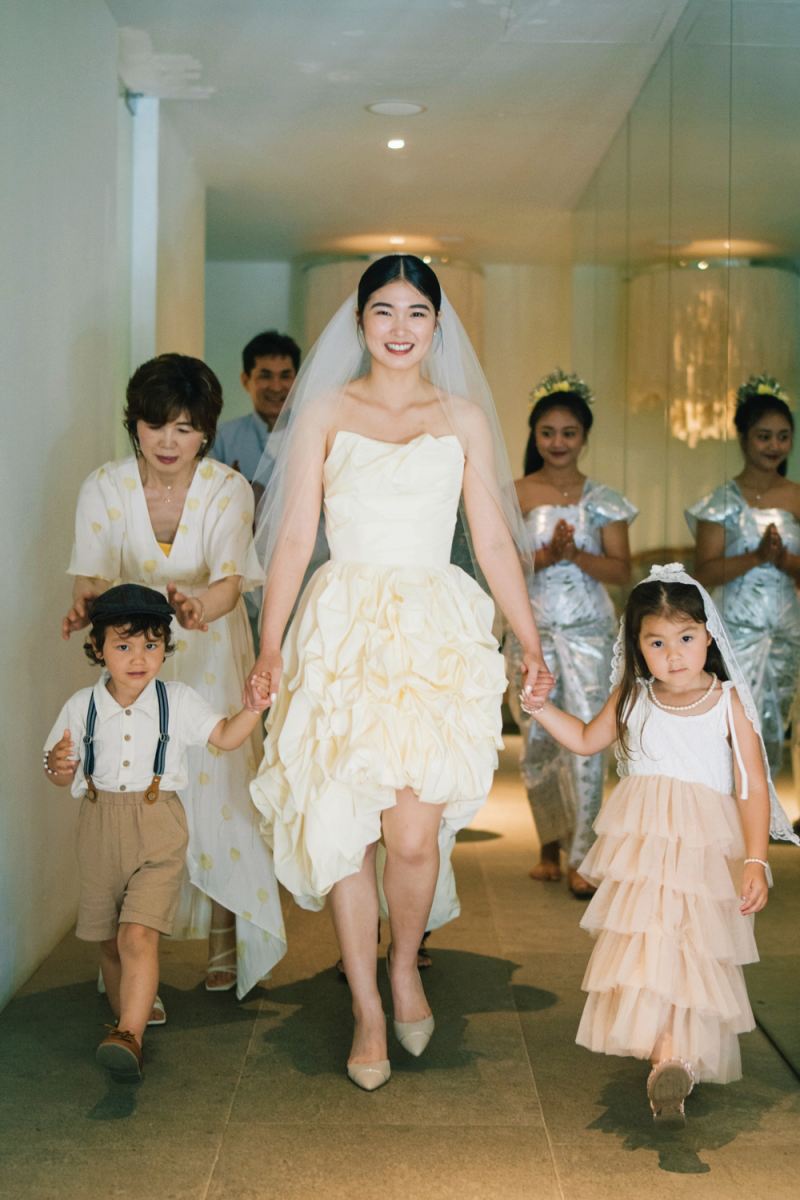 The bride walks hand in hand with the flower children, beaming on her wedding entrance.