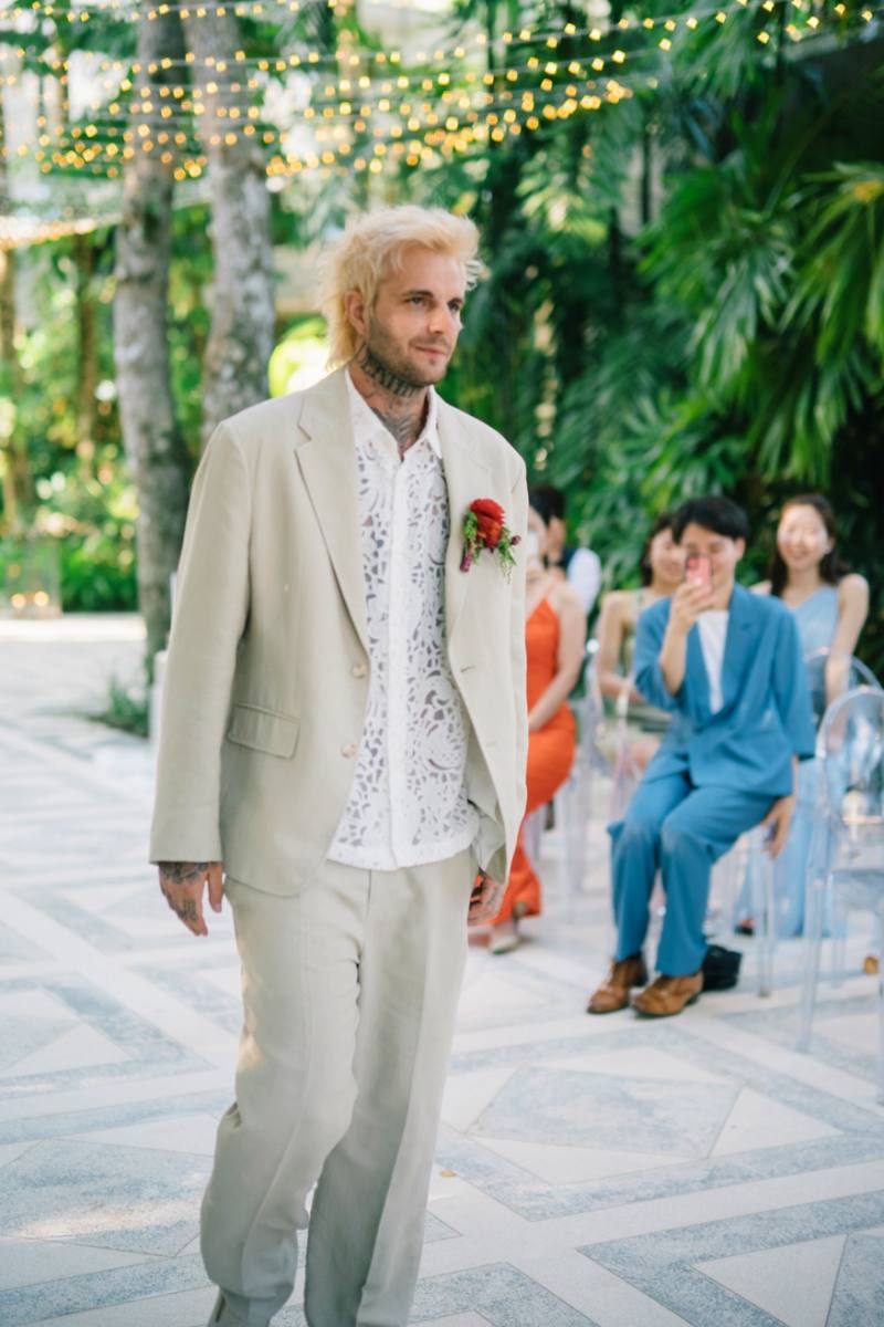 The groom walks into the ceremony at Moonlight Garden, surrounded by tropical beauty.