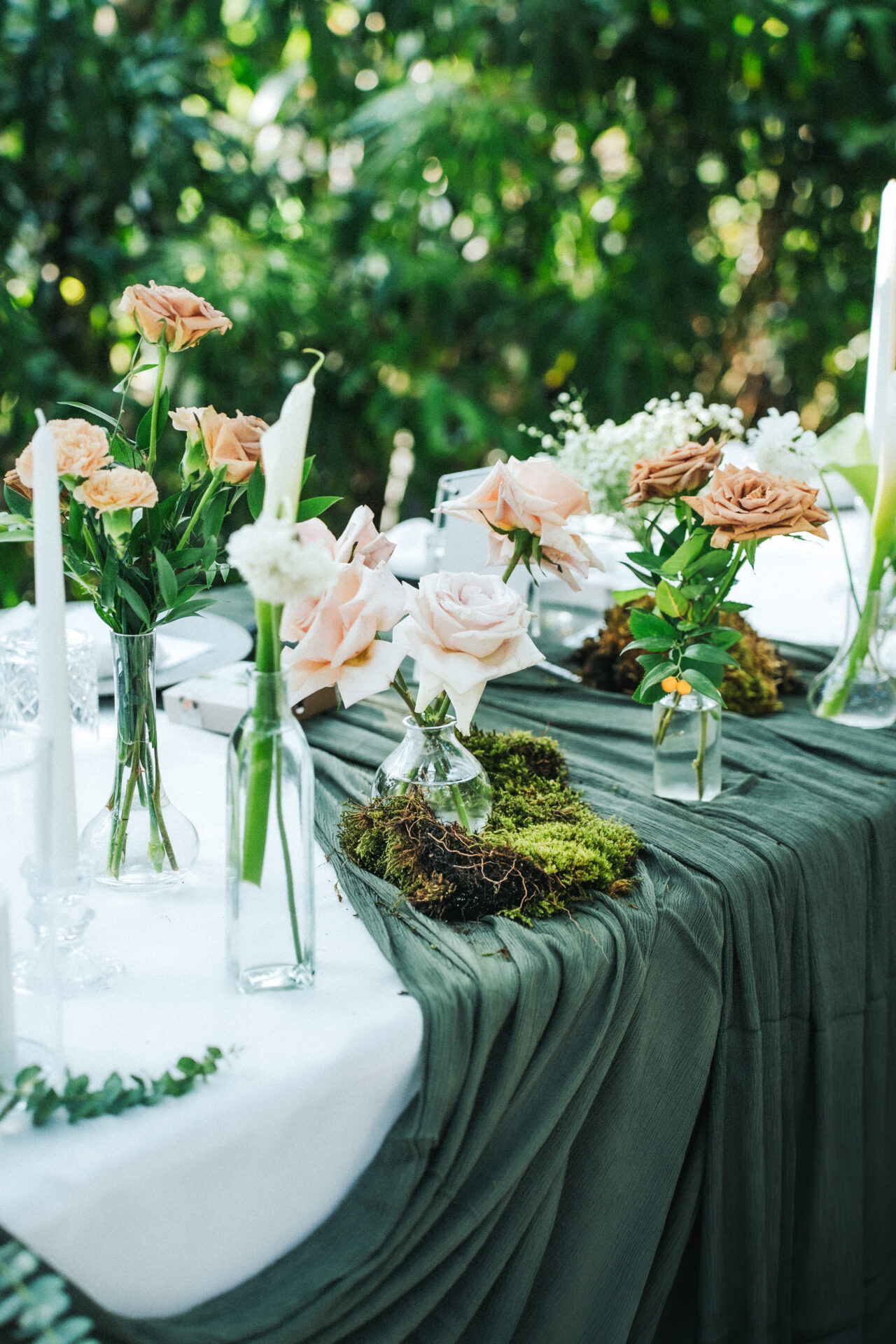 Floral centerpiece of blush roses and moss as part of green wedding decor at Moonlight Garden.