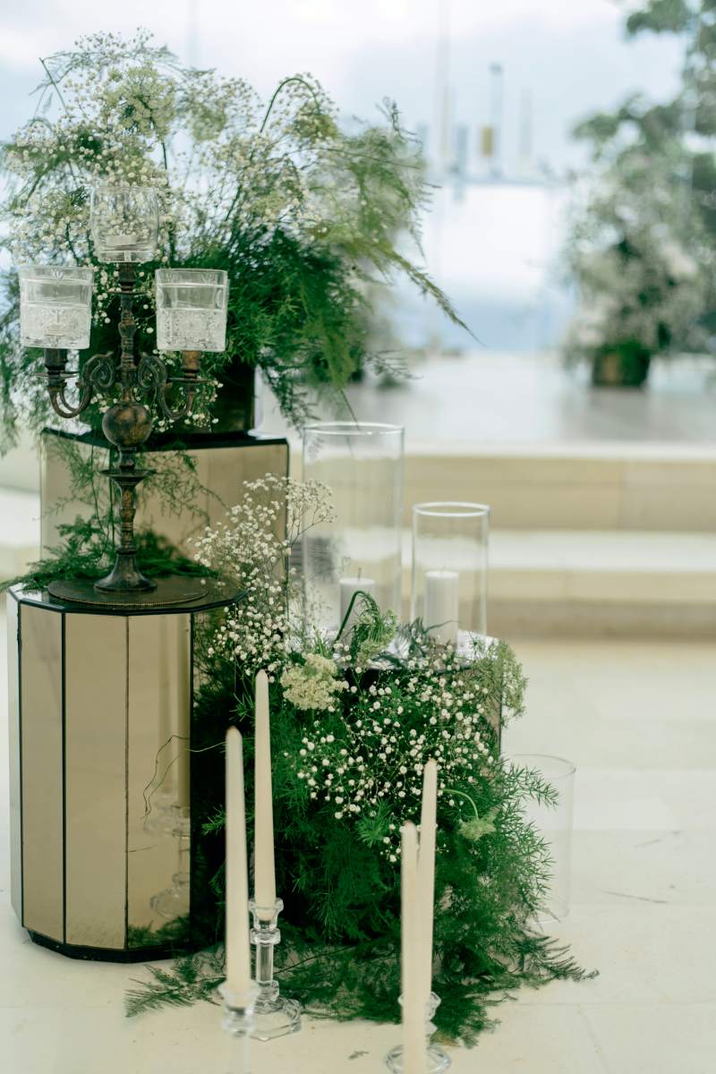 Elegant stands adorned with baby’s breath and crystal candle holders at the glass chapel altar.