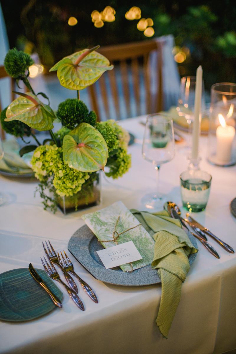 Close-up of tropical green centerpiece and place setting at Moonlight Garden wedding reception.