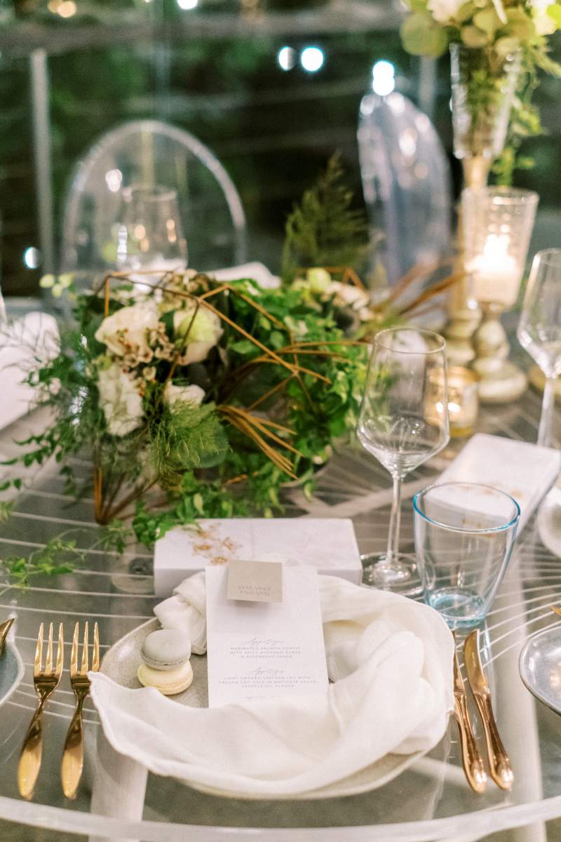 Place setting in the Plumeria Room with gold cutlery, twisted napkin, and macaron.