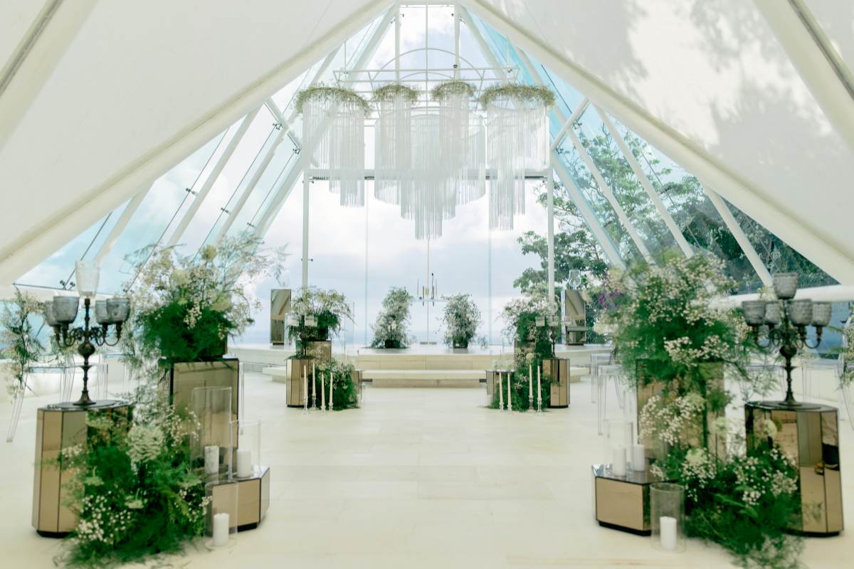 A lush botanical haven lines the aisle inside the glass chapel at Tirtha Uluwatu.