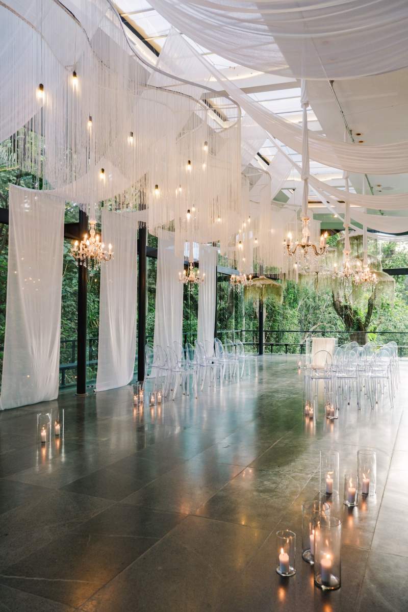Plumeria Room wedding decor with chandeliers, sheer drapes, and candle-lit aisle.