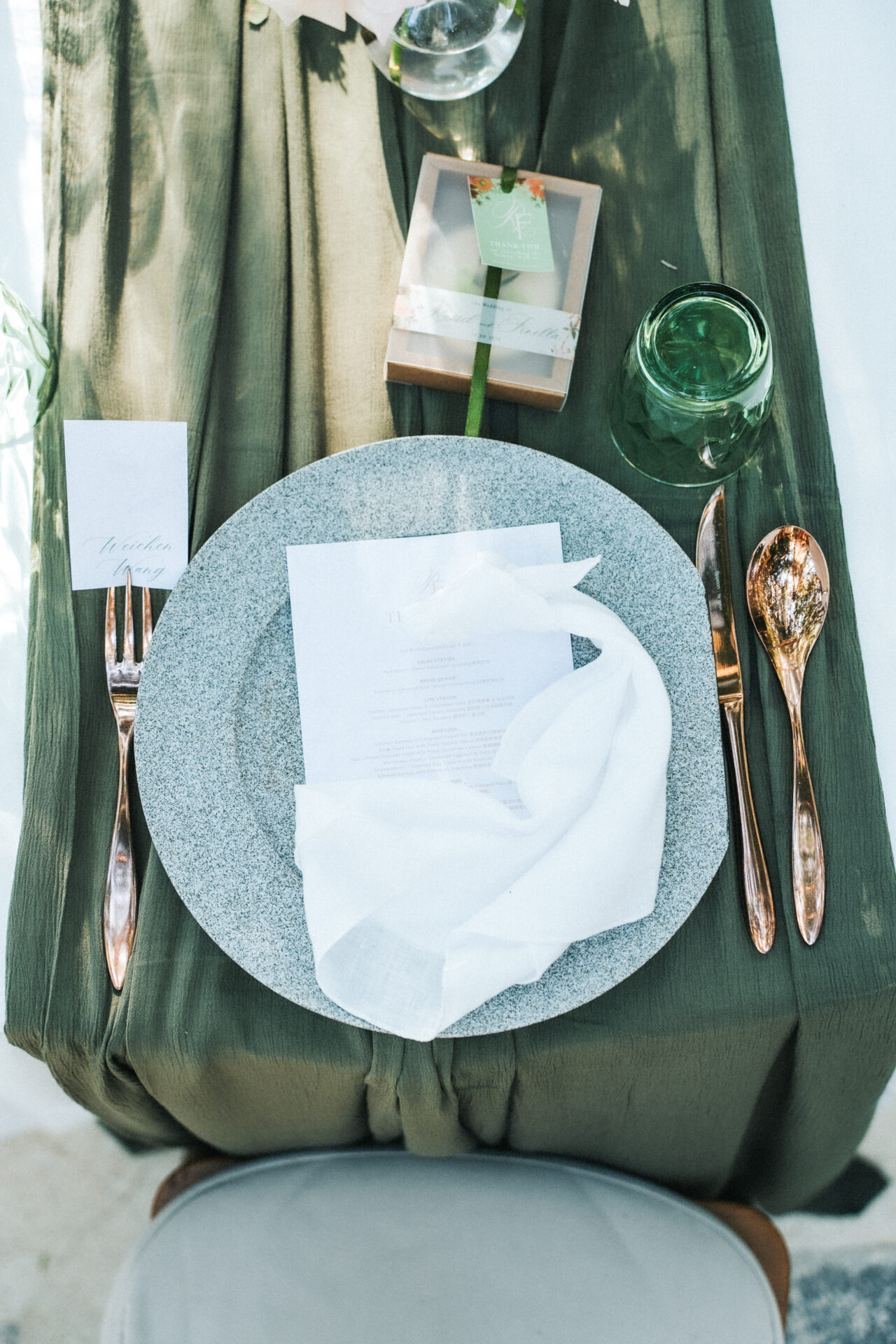 Place setting at Moonlight Garden with stone plate, green glass, and gold cutlery as part of green wedding decor.
