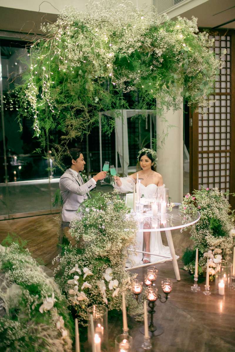 Bride and groom toast under lush green wedding decor in the Heaven Room at Tirtha Bali.