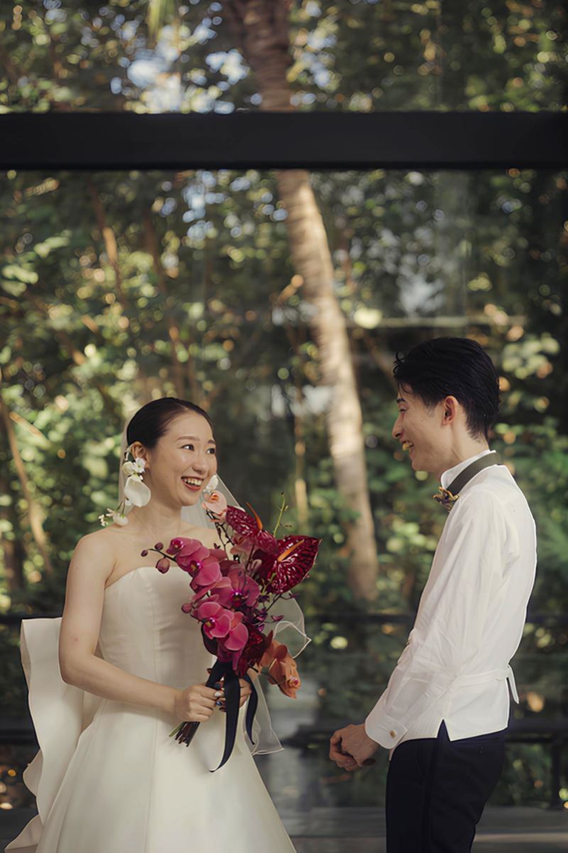 Bride and groom exchange joyful looks while holding hands during Bali wedding shoot.