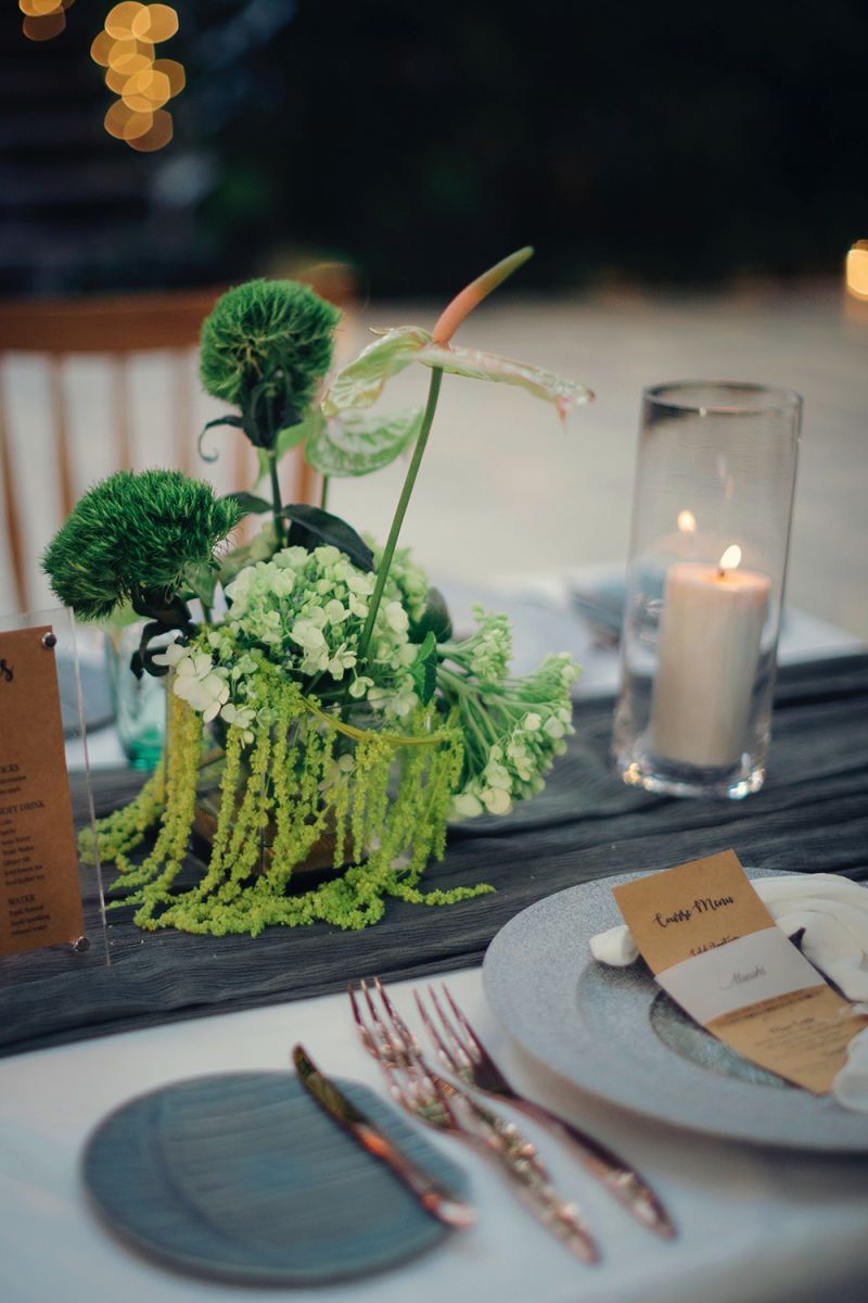 Elegant table decor with green floral centerpiece and candlelight at a wedding in Bali.