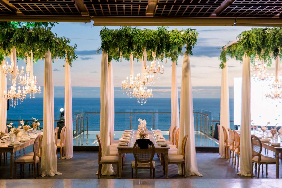 Elegant reception setup on the Glass Stage at Tirtha Uluwatu, overlooking the Indian Ocean at sunset.
