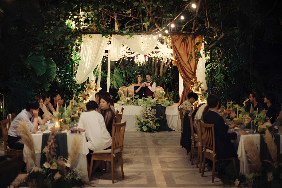 Couple toasting during their evening bali wedding reception surrounded by guests, highlighting a real wedding story at Tirtha.