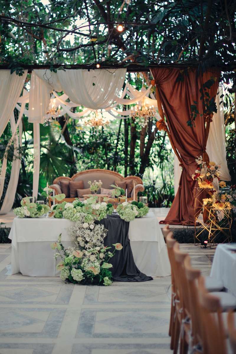 Reception setup at a wedding venue in Bali with greenery, hanging lights, and romantic floral décor.