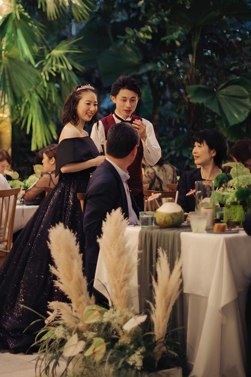 Bride and groom visiting guests during garden wedding reception in Bali at the Glass House by Tirtha.