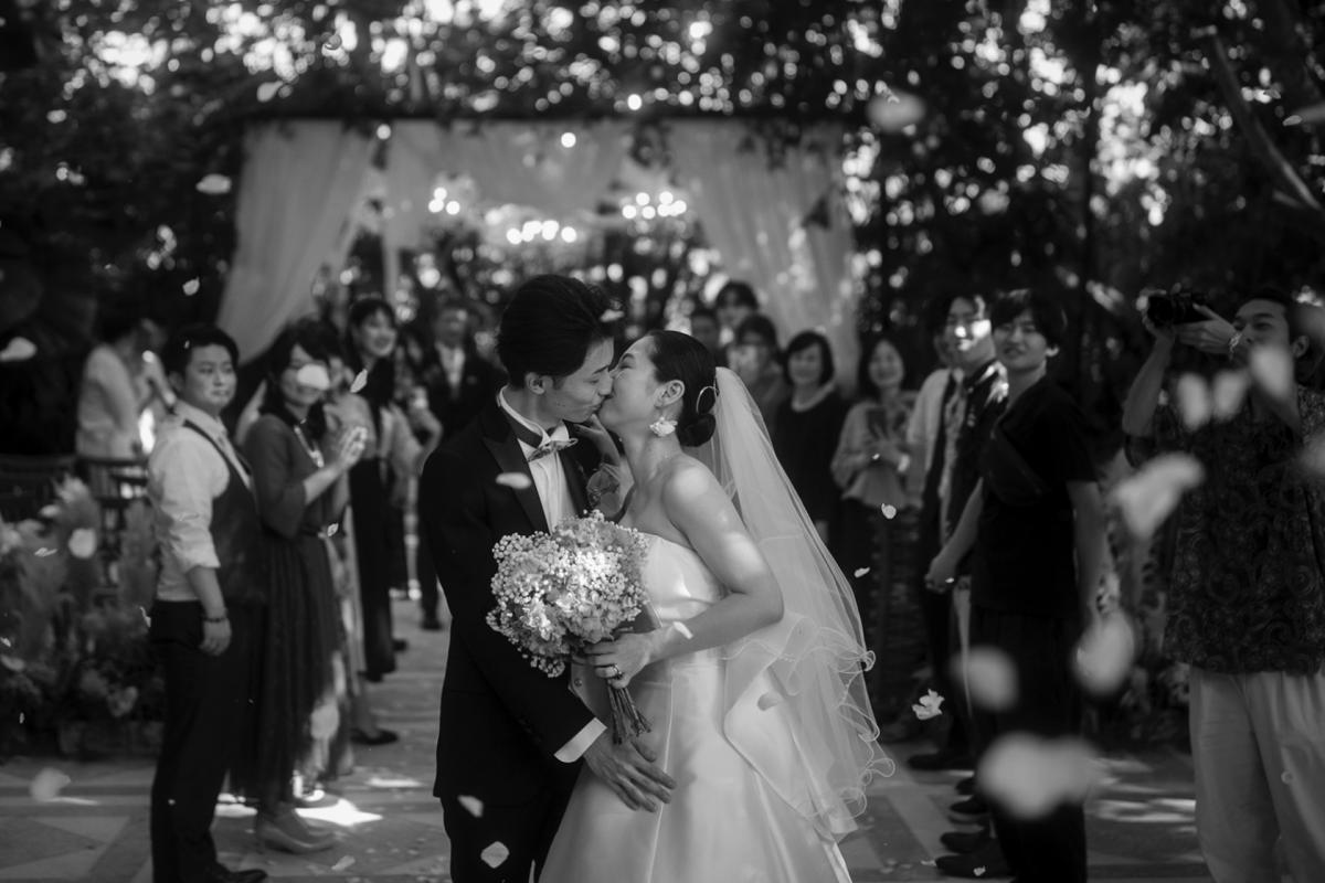 A romantic kiss between the couple as confetti rains down at their Bali garden wedding.