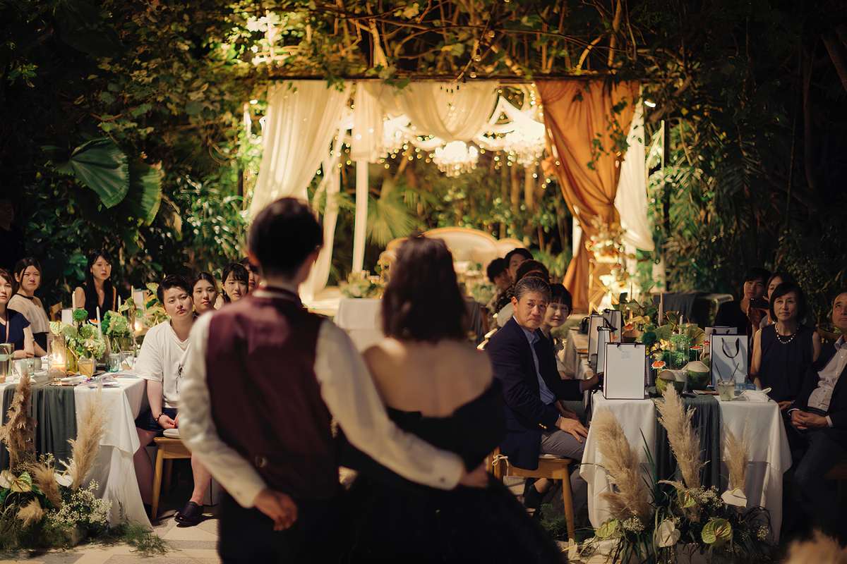 Bride and groom addressing wedding guests under draped canopy and garden lights in a bali destination wedding at Tirtha.