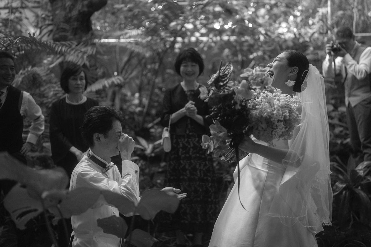 Bride laughs emotionally while groom wipes a tear during their surprise second proposal in Bali.