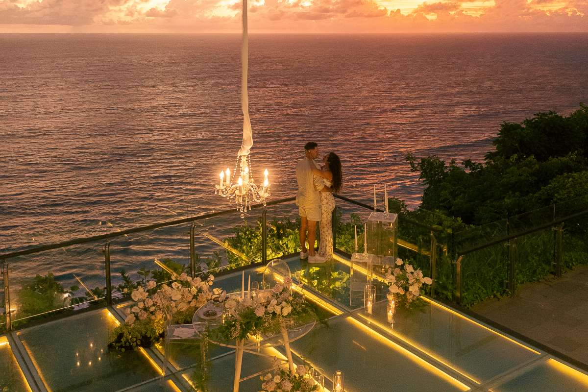 Couple at sunset on glass stage during a cliffside wedding at Tirtha Uluwatu.