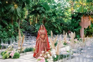 Bride standing on a floral-lined aisle at Moonlight Garden with clear acrylic chairs and pampas grass arrangements.