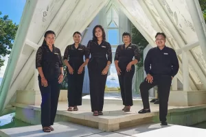 Tirtha Bali's outstanding team stands with smiles in front of Tirtha Uluwatu's iconic glass chapel.