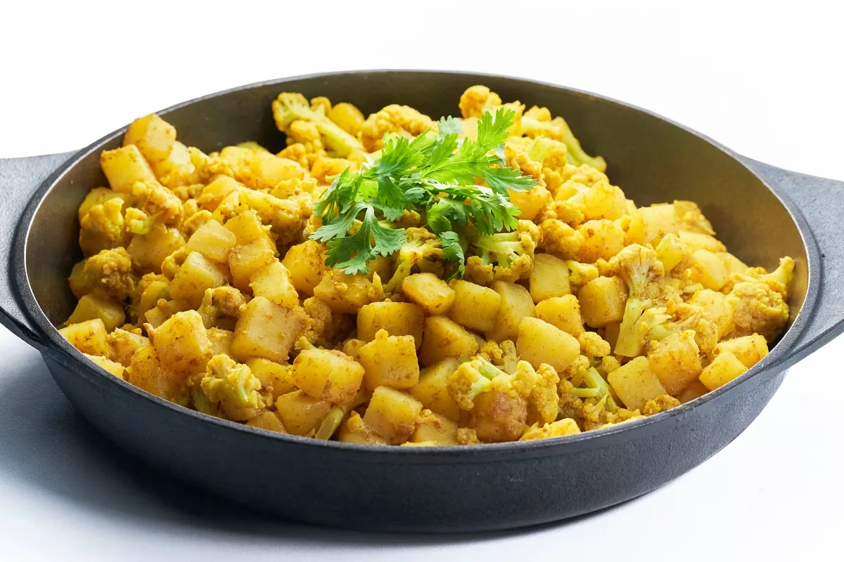 Aloo gobi with potatoes and cauliflower cooked in aromatic spices and garnished with cilantro.
