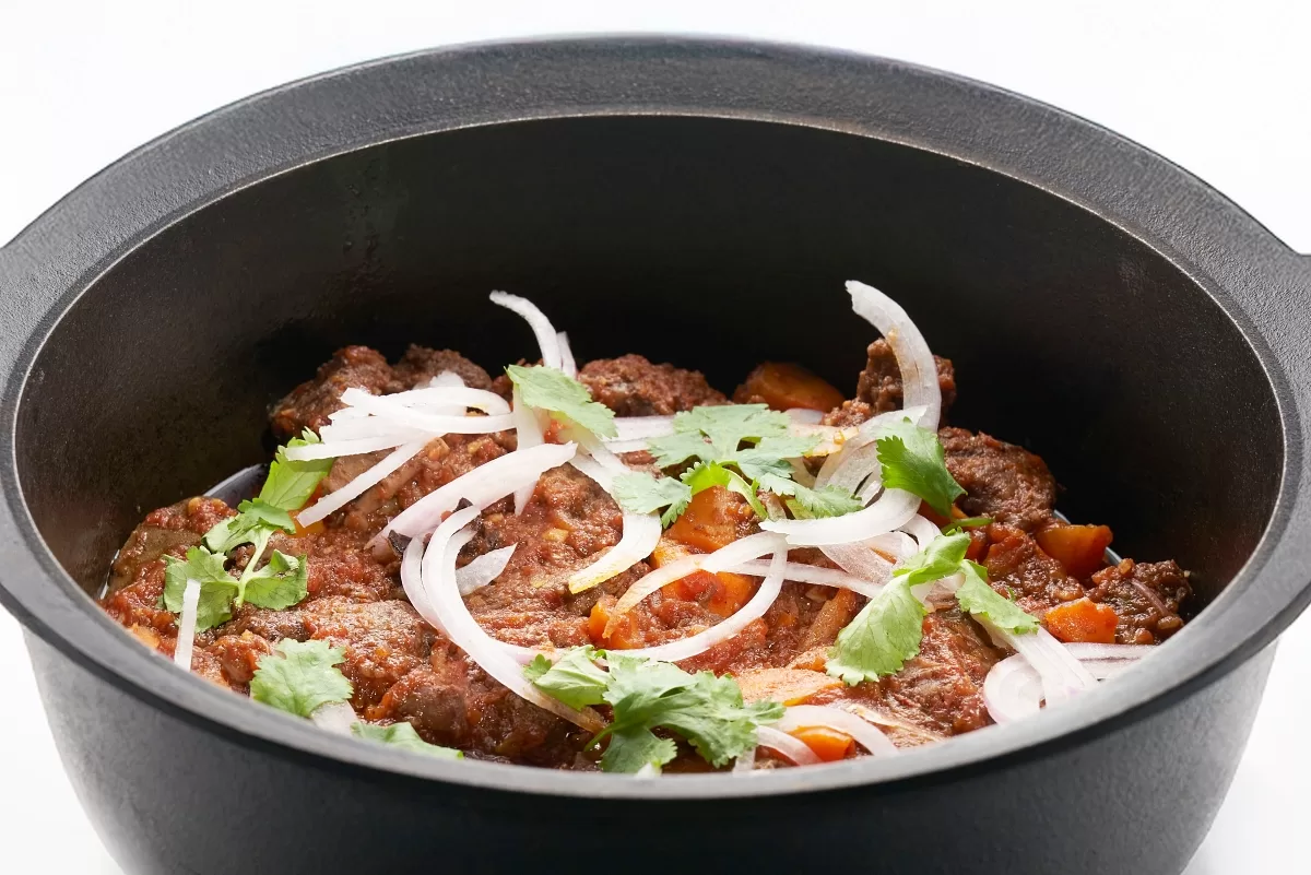 Bo kho with tender stewed beef and carrots, topped with sliced onion and cilantro.