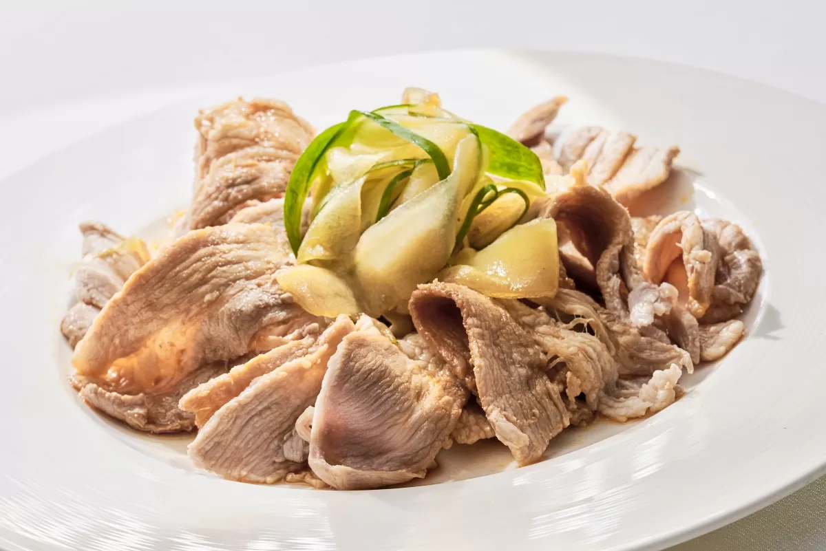 Boiled pork belly salad with thinly sliced pork belly and crisp cucumber on top.