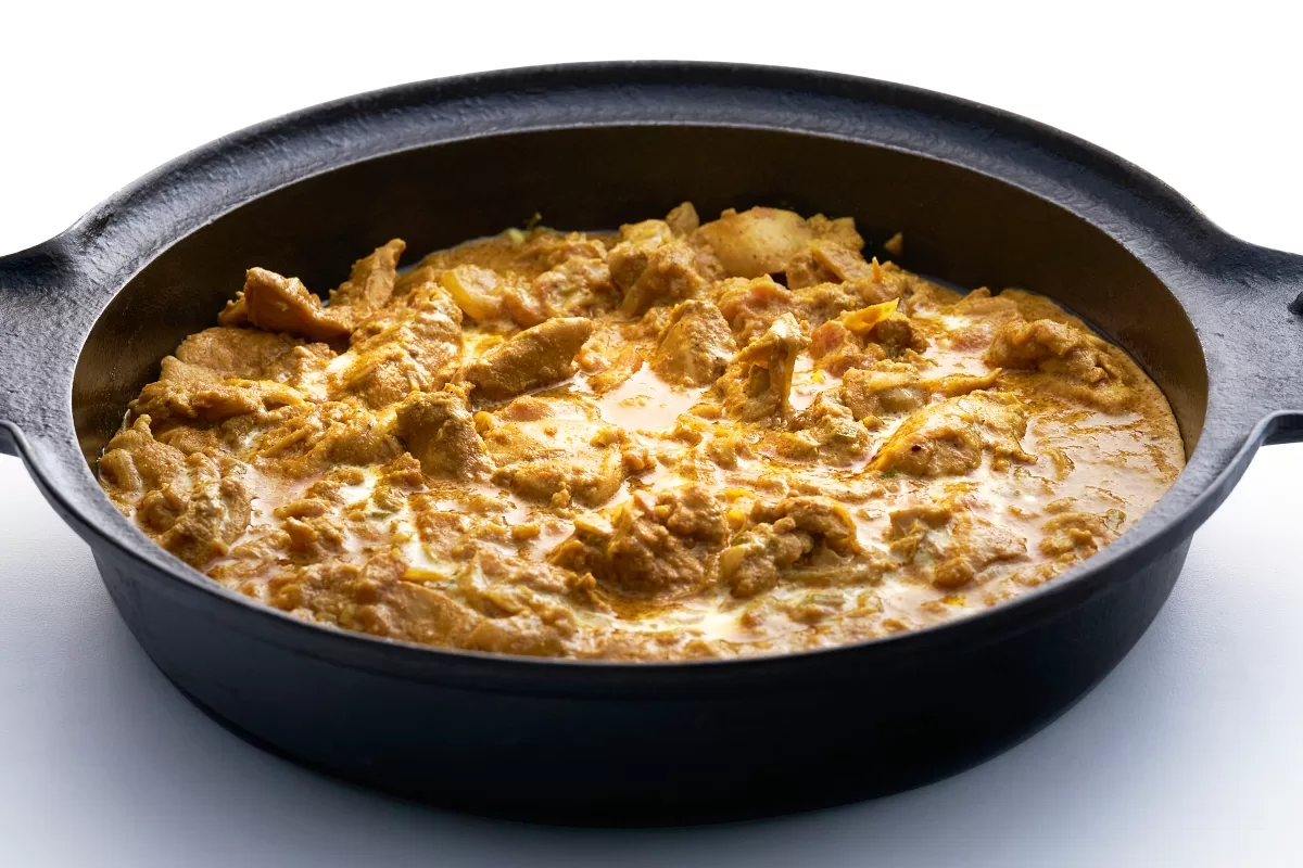 Butter chicken curry served in a shallow pan, featuring tender chicken cooked in a rich, creamy tomato-based sauce.