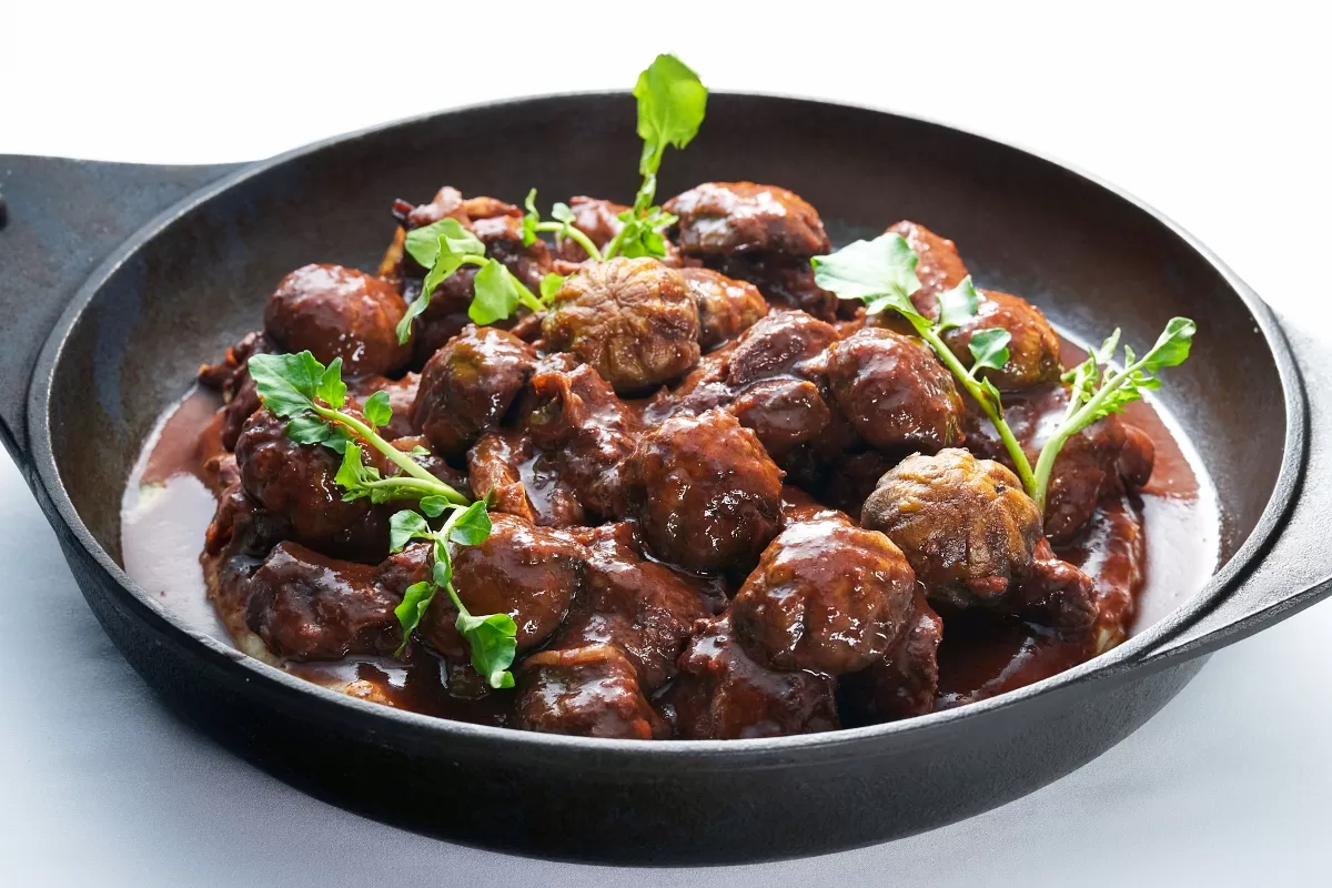 Coq au vin, a classic French dish of chicken stewed in red wine sauce, served in a shallow pan.