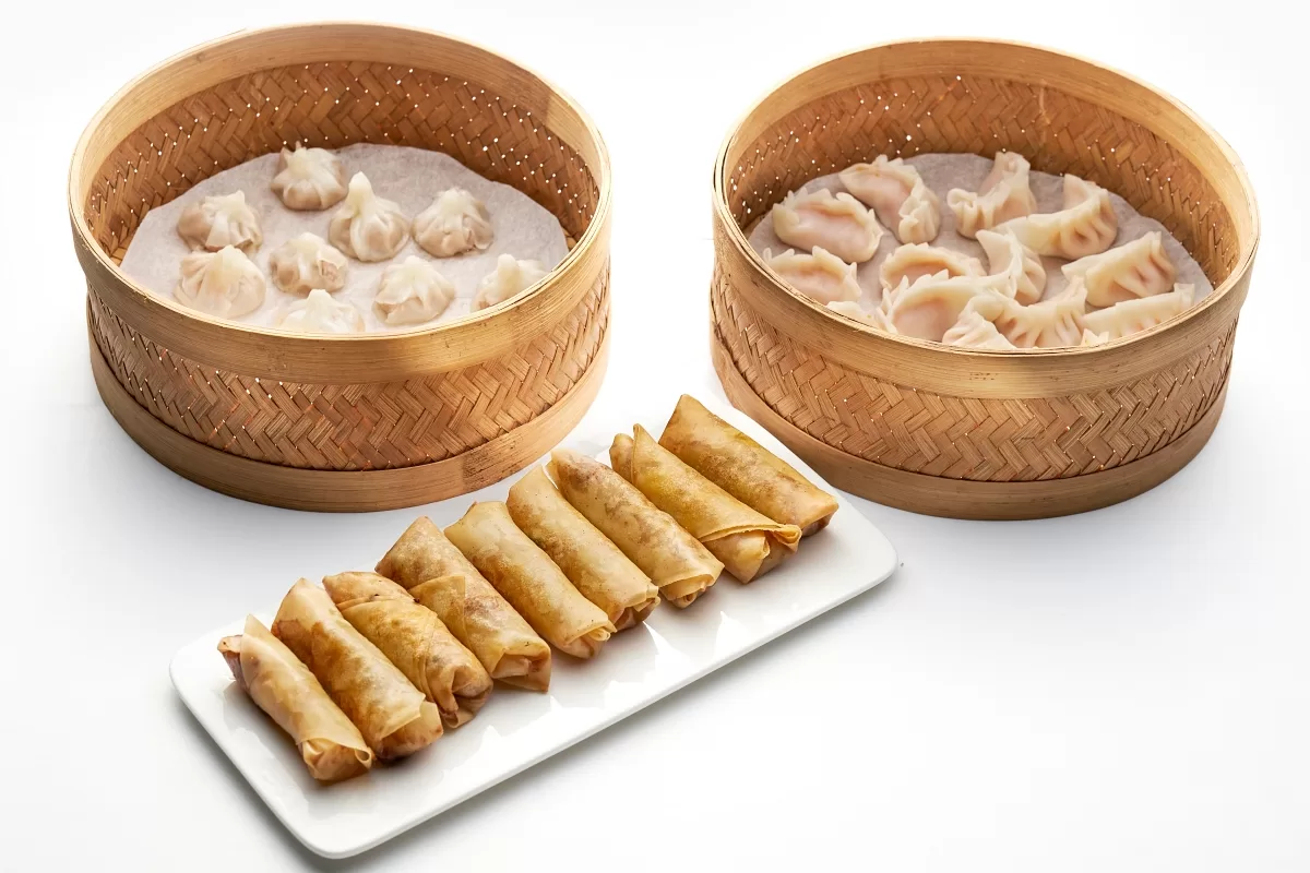 An assortment of dim sum, including pork soup dumplings, prawn dumplings, and crispy pork spring rolls.