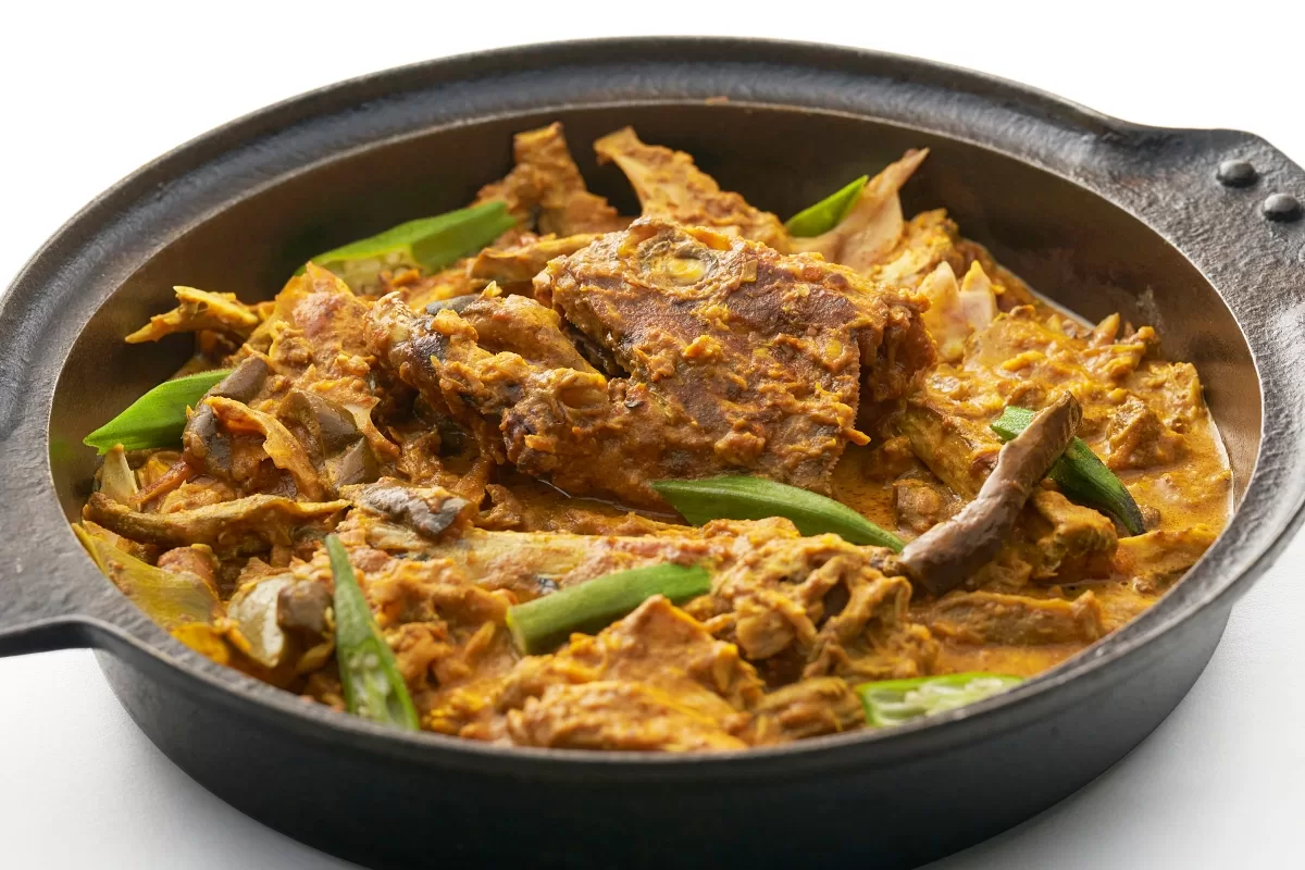 Fish head curry served with long beans in a rich, aromatic spiced sauce.