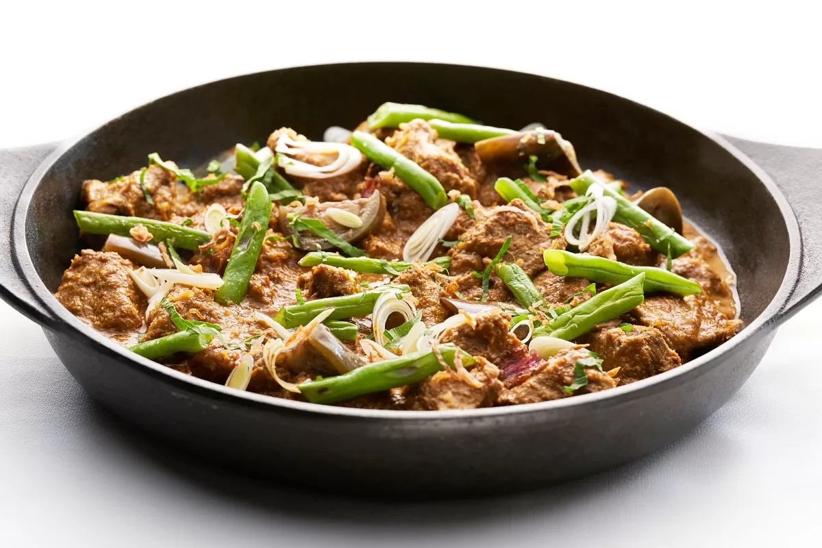 Gulai kambing served in a bowl with tender lamb, green beans, and aromatic spices in a rich curry sauce.