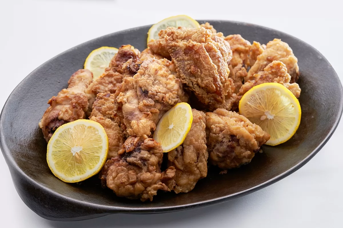 Korean fried chicken with crispy golden coating served with lemon slices.